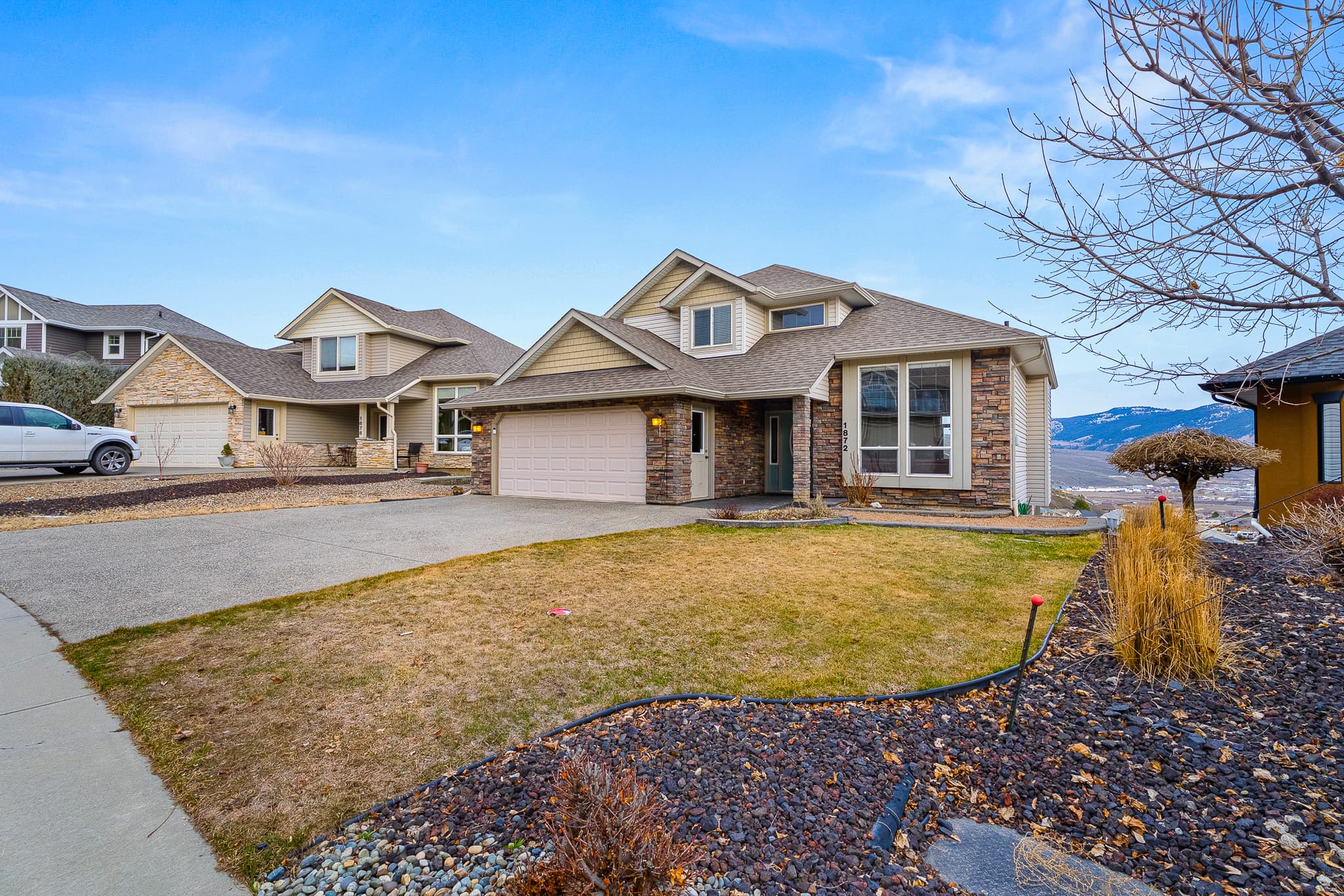 Front exterior with stone and stucco, triple garage