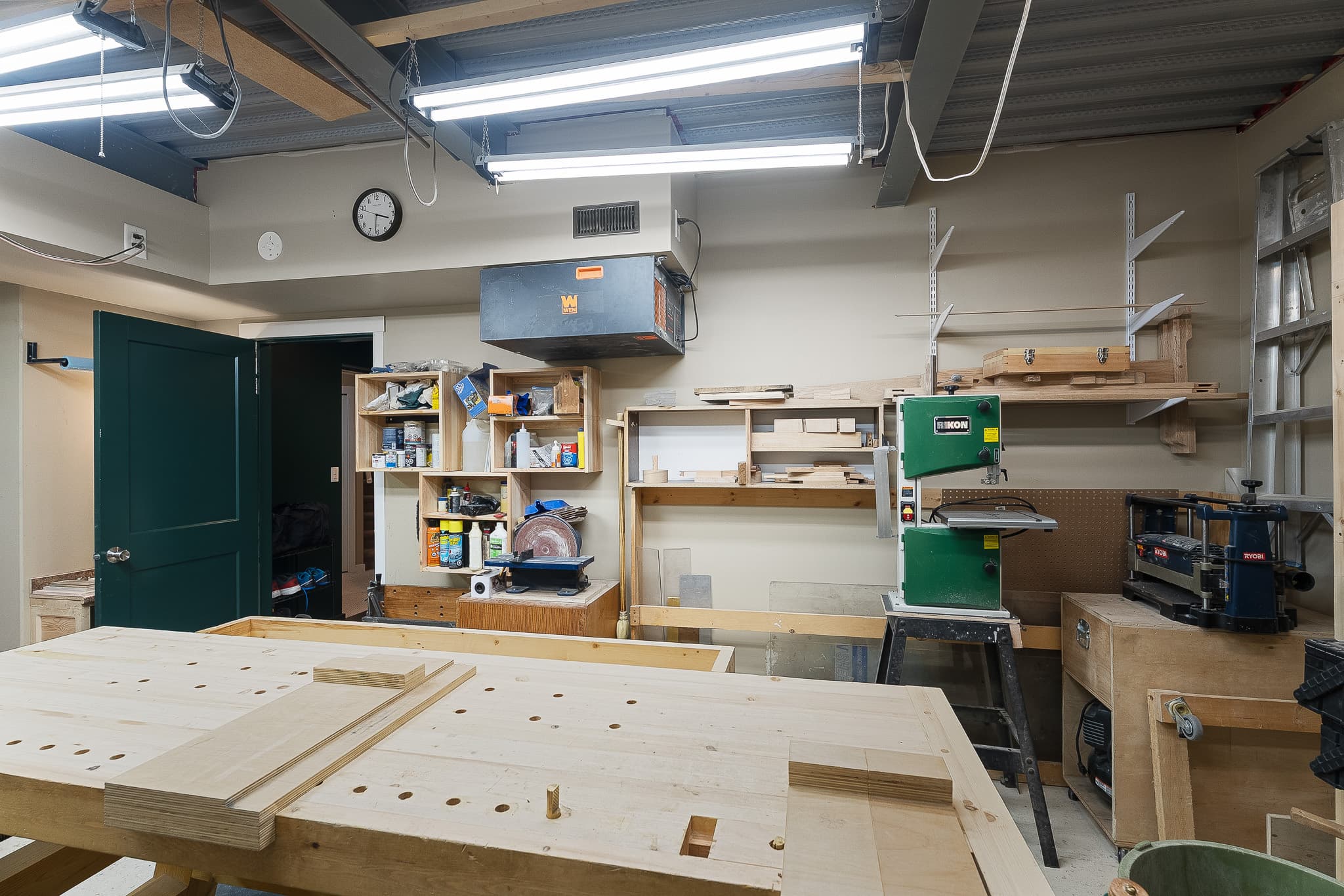 Full workshop with industrial lighting, workbenches, and woodworking tools